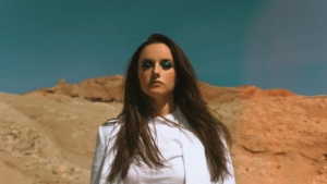 A woman in a white blazer standing in the desert.