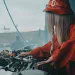 A woman in a red hat is playing a dj set.