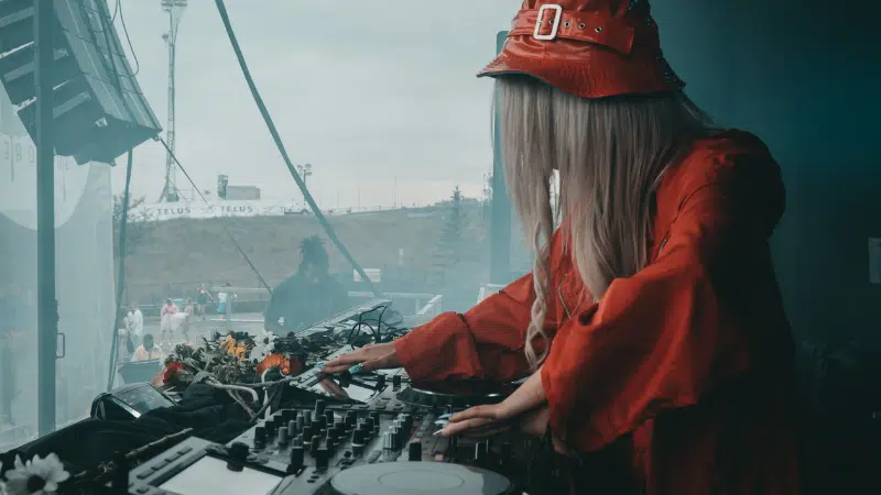 A woman in a red hat is playing a dj set.