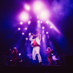 A man on stage with a purple light behind him.