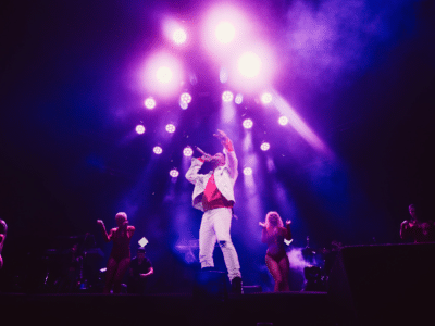 A man on stage with a purple light behind him.