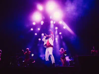 A man on stage with a purple light behind him.