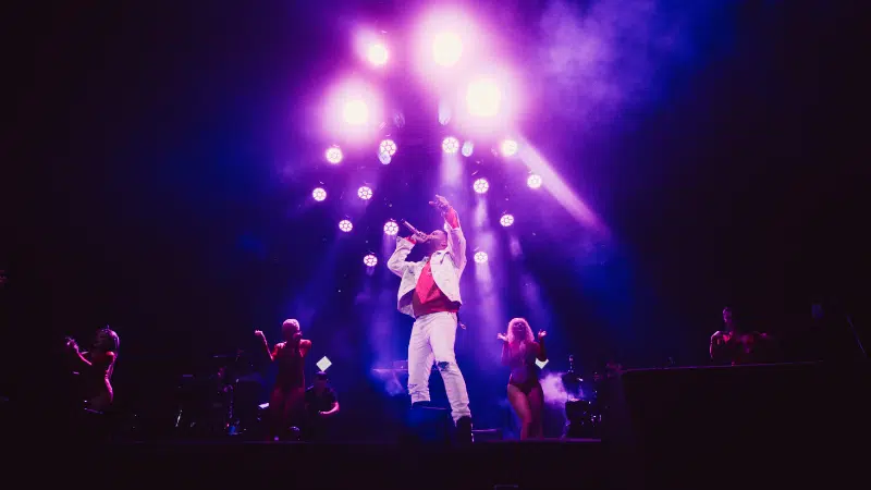 A man on stage with a purple light behind him.