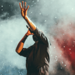 A man with his hands up in the air at a concert.