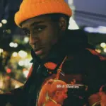 A young man wearing an orange hat and jacket.