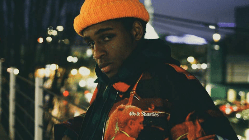 A young man wearing an orange hat and jacket.