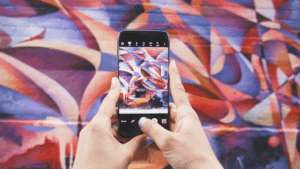 A person taking a photo of graffiti on a cell phone.