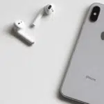 An iphone xs and a pair of earphones on a white surface.