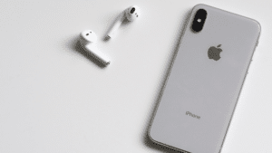 An iphone xs and a pair of earphones on a white surface.