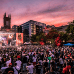 A crowd of people at a music festival at dusk.