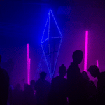 Silhouettes of people standing in a dark room with neon lights.