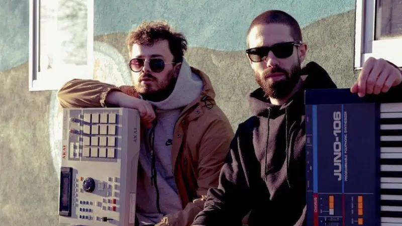 Two men standing next to each other holding electronic keyboards.