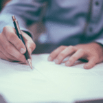 A man signing a document with a pen.