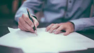 A man signing a document with a pen.