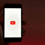 A person holding a phone with the youtube logo on it.