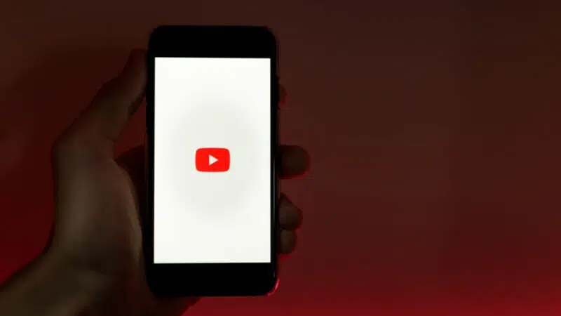 A person holding a phone with the youtube logo on it.