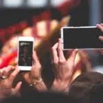 A group of people taking pictures with their cell phones.