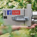 A person holding a camera with the facebook live logo on it.