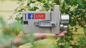 A person holding a camera with the facebook live logo on it.
