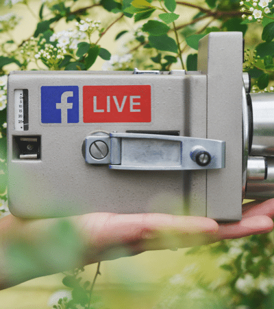 A person holding a camera with the facebook live logo on it.