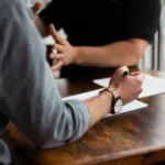 Two people sitting at a table talking to each other.