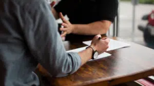 Two people sitting at a table talking to each other.