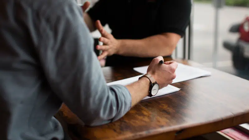 Two people sitting at a table talking to each other.