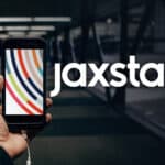 A person holding up a phone with the jaxsta logo on it.