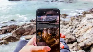 A person holding up a phone with a picture of the ocean.