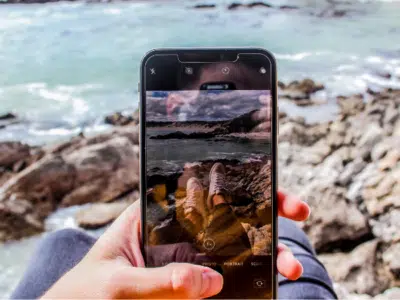 A person holding up a phone with a picture of the ocean.