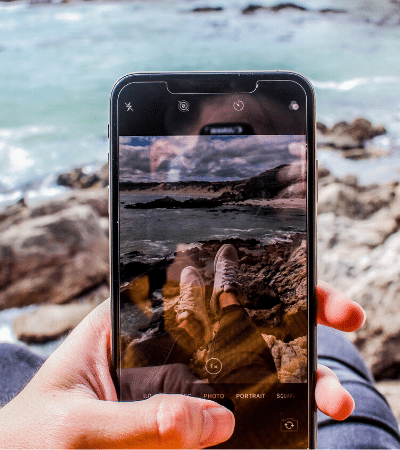 A person holding up a phone with a picture of the ocean.