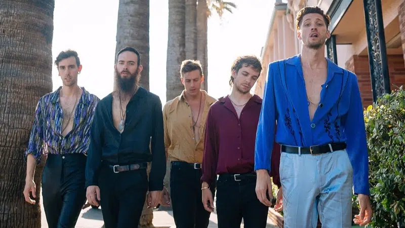 A group of young men standing in front of palm trees.