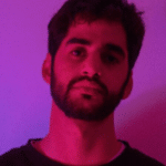 A man with a beard standing in front of a purple light.