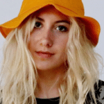 A blonde woman wearing an orange bucket hat.