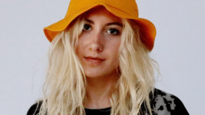 A blonde woman wearing an orange bucket hat.