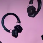 A group of headphones on a pink background.