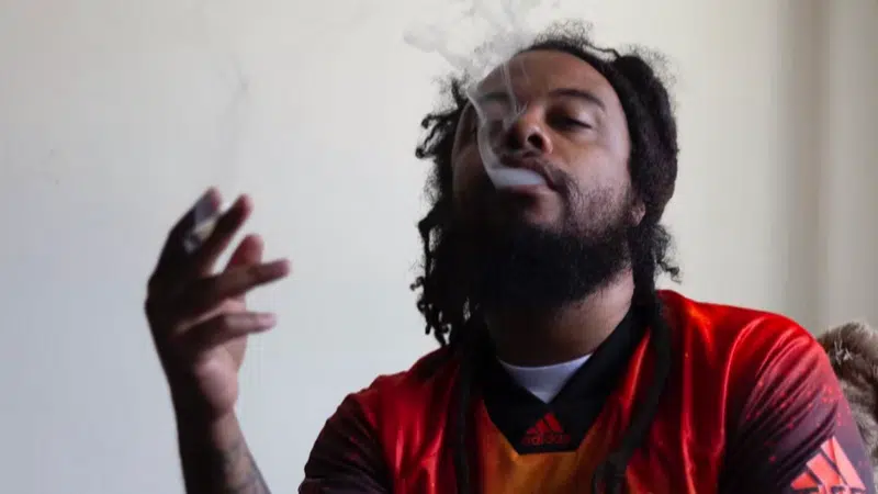 A man with dreadlocks smoking a cigarette.