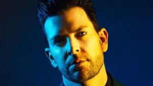 A man in a suit with a blue background.