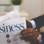 A man holding a newspaper with the word business on it.