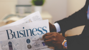 A man holding a newspaper with the word business on it.