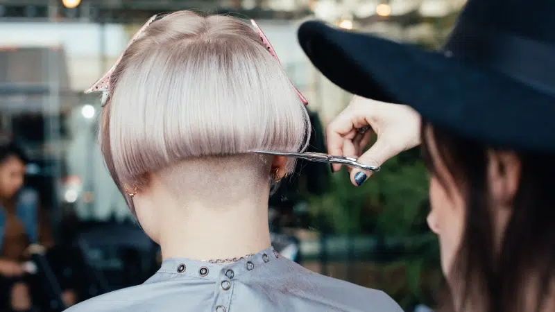 A woman is getting her hair cut in a salon.