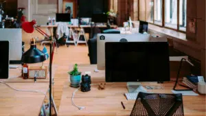 An empty office with two monitors and a lamp.