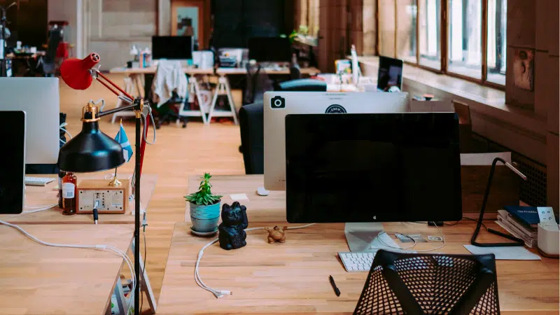 An empty office with two monitors and a lamp.
