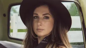 A woman in a hat sitting in the back seat of a truck.