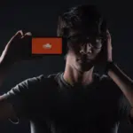 A man holding up a phone with an orange screen on it.