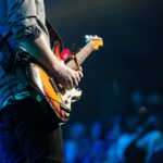 A man playing an electric guitar in front of a crowd.