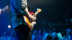 A man playing an electric guitar in front of a crowd.