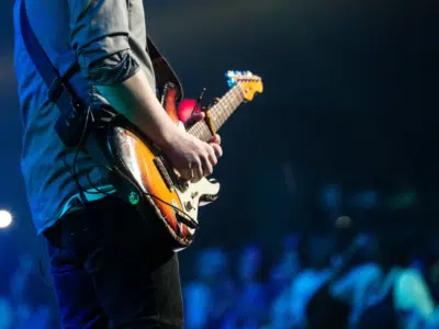 A man playing an electric guitar in front of a crowd.