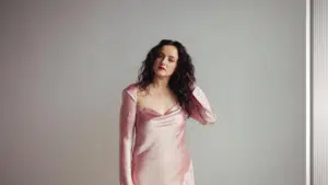 A woman in a pink dress posing in front of a mirror.