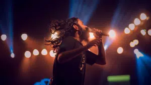 A man with long hair singing into a microphone.